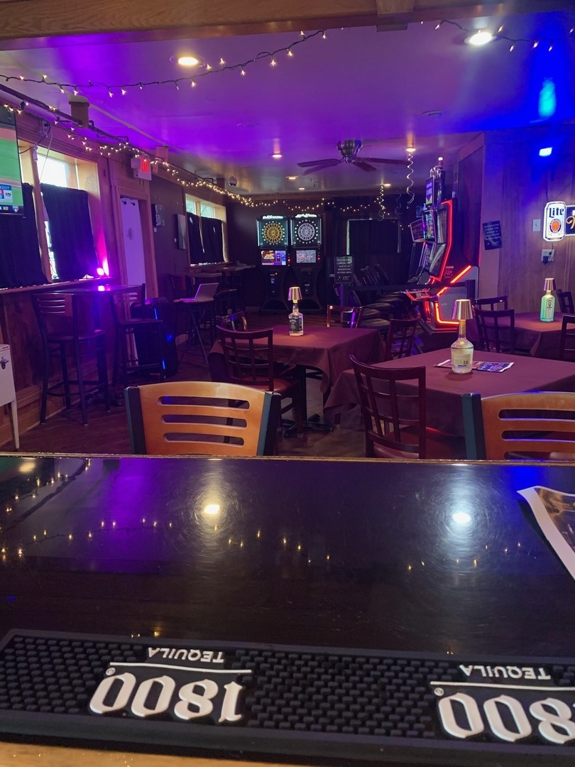 Bar lounge area with tables, darts, and gaming machines
