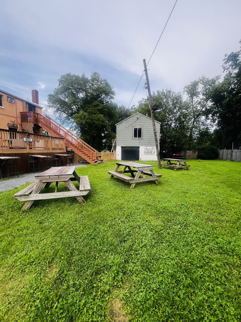 Large grassy yard with picnic tables and the additional building
